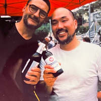 Two Keen employees smiling and clinking bottles